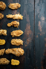 Homemade crispy fried chicken on old dark wooden table, top view, with copy space
