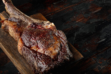 Grilled black angus beef tomahawk steak on bone, on wooden serving board, on old dark  wooden table...