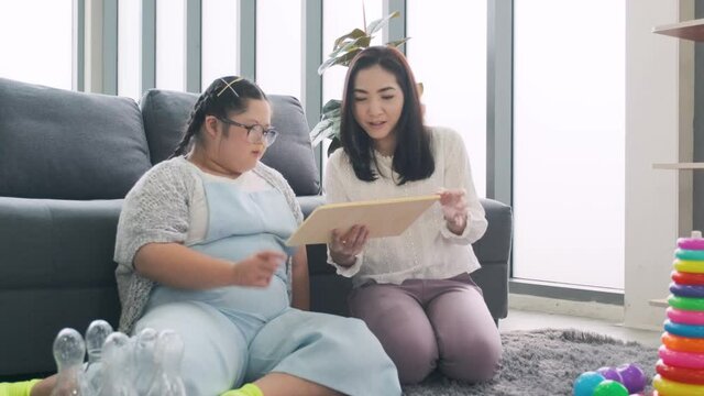 Young woman and little girl with down syndrome disorder playing at home