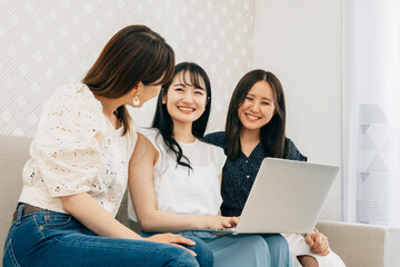 家でパソコンを使う女性たち（笑顔）
