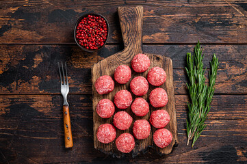 Uncooked Raw meatballs from ground beef and pork meat with rosemary. Dark Wooden background. Top...