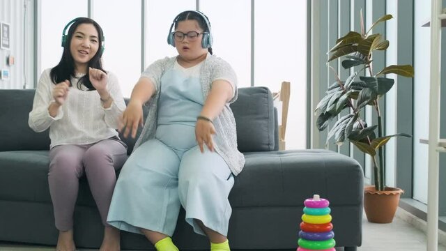 Down syndrome girl is listening to music and singing with her mother holiday home.