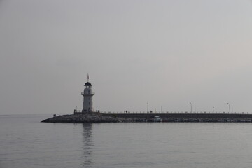 Silhouettes of the lighthouse and pier on a cloudy day against the backdrop of a calm sea, Alanya, November 2021