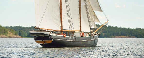 An elegant two-masted gaff schooner (training tall ship) sailing in Mälaren lake, Sweden. Travel, history, traditions, transportation, sailing, sport, cruise, regatta, teamwork. Panoramic view