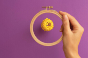 Yellow curly embroidery thread through the embroidery ring on a purple background