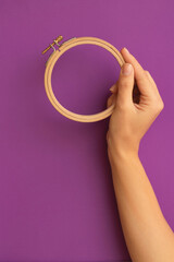 wooden Embroidery ring in hand on a purple background