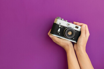 Analog black and white camera in hands on a purple background
