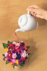 White teapot embroidery threads and floral decoration in a tea cup on a wooden background