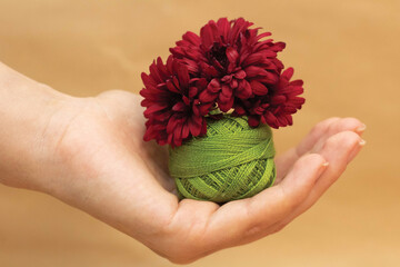 Green embroidery thread and red flower in hand