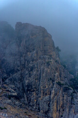 Stony slopes of mountain in dense fog.