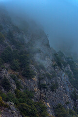 Stony slopes of mountain in dense fog.