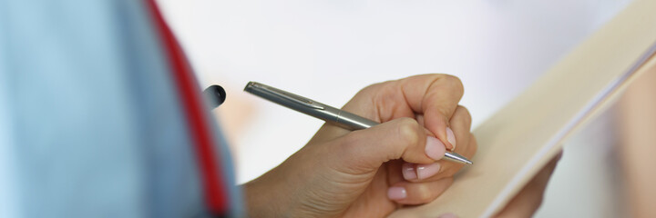 Doctor filling out patient medical documents with ballpoint pen in ward closeup