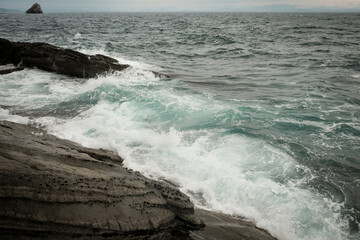sea waves with splashes and foam wash over the rocky stones