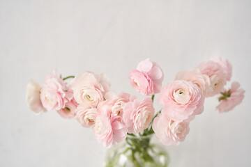 The background of ranunculus colors is gently pink. A riotous peony-shaped rose bouquet