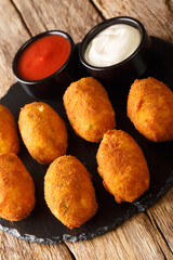 Salt cod croquettes croquetas de bacalao with sauces close up in the slate plate on the table....