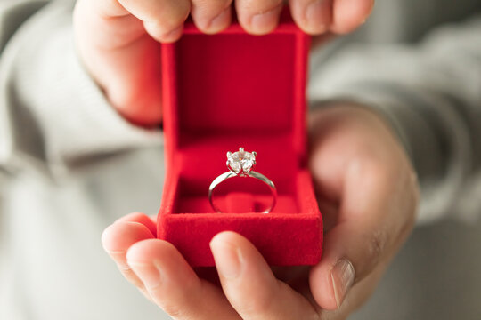 hands holding diamond ring in jewelry box