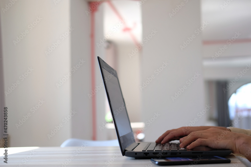 Aufkleber man typing on a laptop computer while sitting at a white office work table with a cup of coffee and 