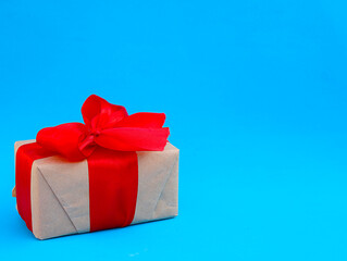 gift box made of kraft paper with a red ribbon on a blue background