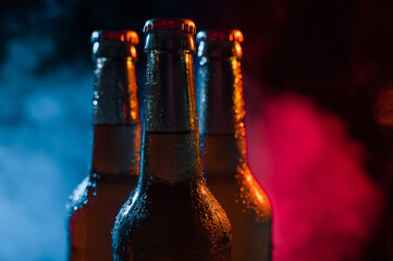 Three bottles of beer in a blue-pink mist.