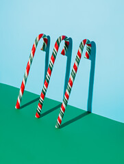Red and Green Christmas candy canes leaning on the bright blue wall. Festive candies and sweet food. Creative Xmas and New Year creative concept. December winter holidays idea.