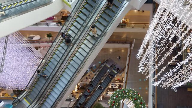 Crowd of People on an escalator in a large multi-storey layered shopping center. View from above