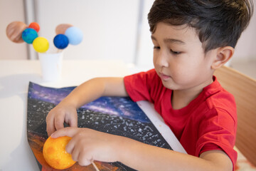 Happy preschooler holding handmade model of the sun. 3D solar system. Homeschool education. Astronomy objects.