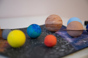 Close up view kid holding a handmade model of planet in 3D solar system. Home education. Studying astronomy, space, planets.