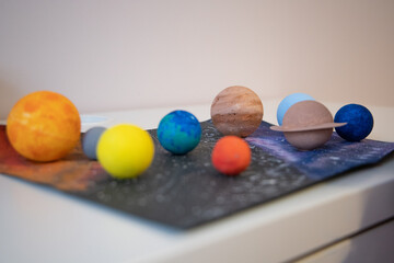 Close up view kid holding a handmade model of planet in 3D solar system. Home education. Studying astronomy, space, planets.
