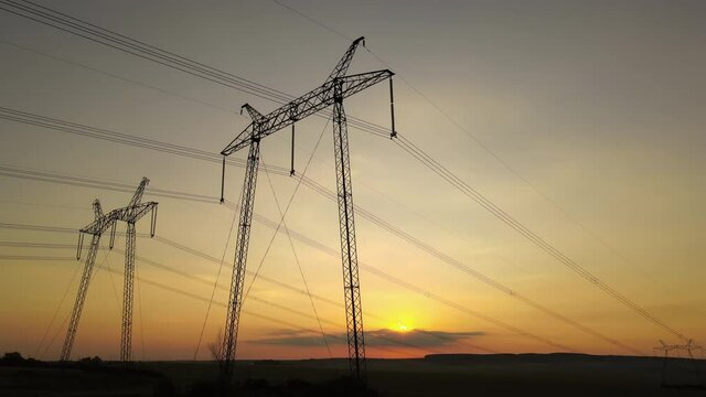 High voltage towers with electric power lines at sunset