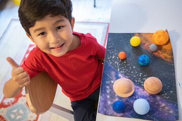 Happy preschooler made a solar system model. Handmade models of planets. 3D solar system. Homeschool education. Astronomy objects. Space colour