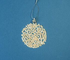 Christmas decoration on a tree in the form of a ball of pasta on a blue paper background, top view. Conceptual photo.