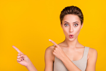 Photo of excited shocked lady direct fingers empty space novelty wear grey top isolated yellow...
