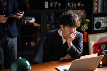 A handsome Asian (Japanese) businessman man thinking while looking at his computer.	