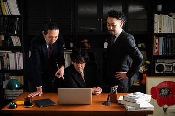 パソコンをみながら考えるチームで仕事をしているアジア系のビジネスマン　クローズアップ	
