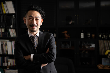Fototapeta premium Handsome Asian (Japanese) businessman man with crossed arms smiling at the camera, copy space at right.