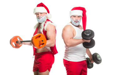 Obraz premium Christmas. Portrait of two strong muscular bearded athletes in Santa Claus costumes, training by lifting barbells isolated on white background
