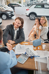Young man with family shaking hands with sales agent after a successful car buying