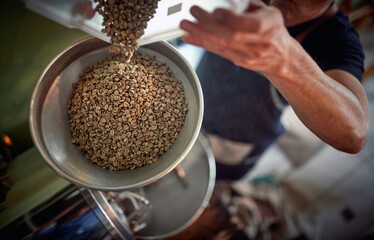 A man is pouring coffee beans into the grinder. Coffee, beverage, producing