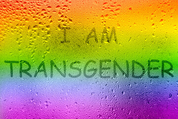 The inscription on the sweaty glass. The word I AM TRANSGENDER written on glass with rainbow