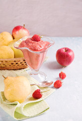 Fruit smoothie- apples, pears and raspberries in a glass glass on a light background. Fruit in a wicker plate on the table.