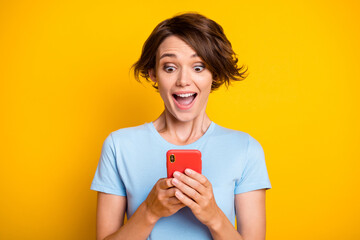 Photo of young blogger happy smile amazed surprised like repost use smartphone isolated over yellow color background