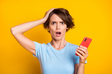 Photo of young woman unhappy amazed shocked hand touch head crazy use smartphone isolated over...
