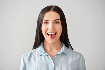 Young woman taking pill on grey background
