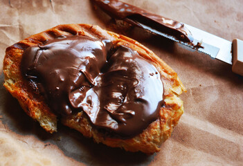 Toasted bread with hazelnut chocolate and a knife on a baking sheet