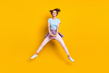Fototapeta na wymiar Photo portrait full body view of funny woman with tight waist shirt jumping up isolated on vivid yellow colored background