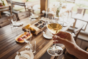 female hand with delicious red wine at a winery during a special tour. Delicacies snacks and appetizers on the table