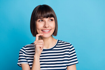 Photo of positive young minded happy woman look empty space hold finger chin isolated on blue color background
