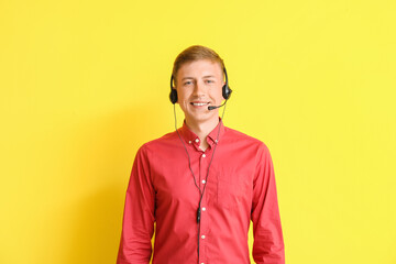 Young consultant of call center in headset on yellow background