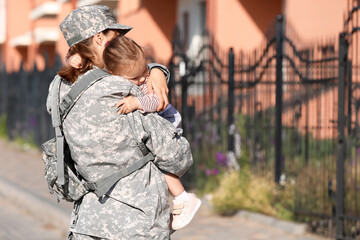 Female soldier with her little daughter outdoors