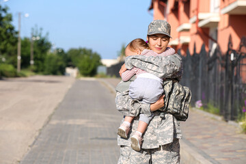 Female soldier with her little daughter outdoors